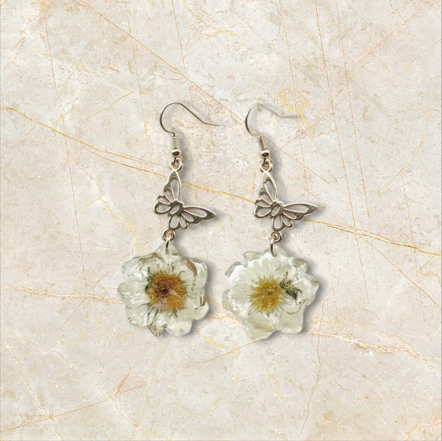 Alyssa's House vintage-style earrings featuring gold-tone butterfly charms and cream pressed flower resin pendants.