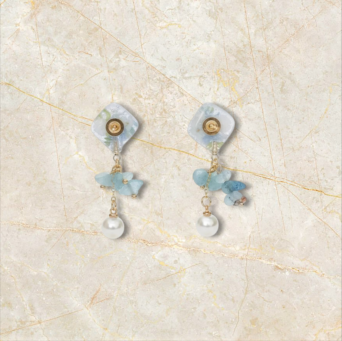 Alyssa's House blue floral square resin drop earrings with stone chips and a pearl dangle on a gold setting.