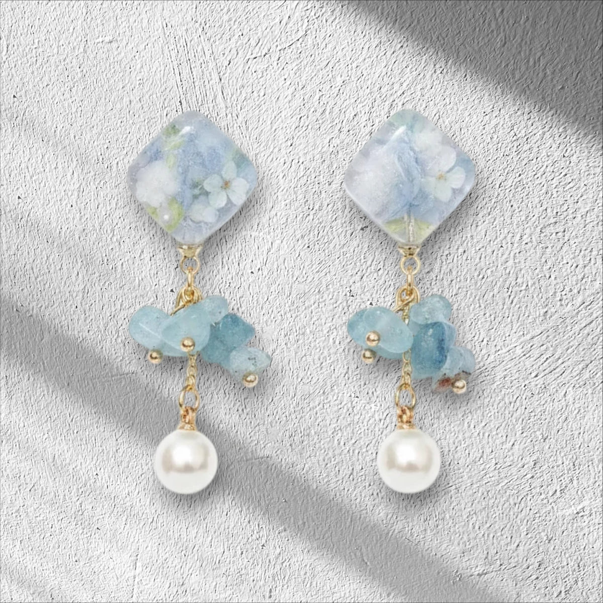 Alyssa's House blue floral square resin drop earrings with stone chips and pearl accents on a white background.