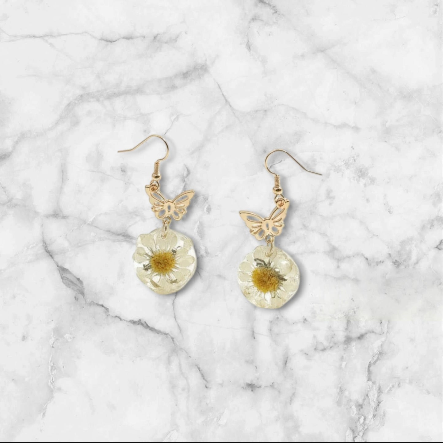 Alyssa's House gold-tone butterfly earrings featuring cream pressed flowers in a whimsical vintage style.