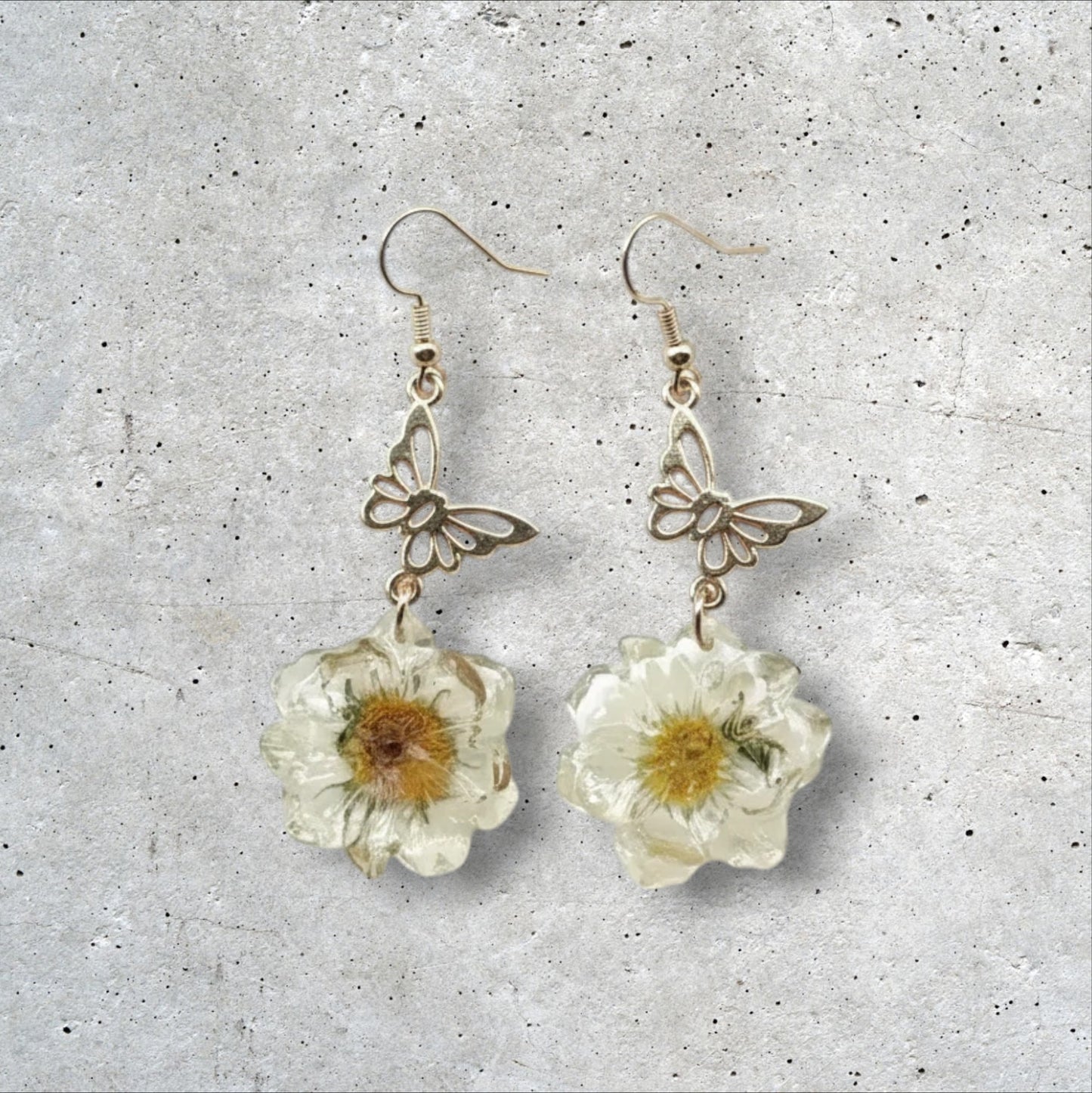 Alyssa's House gold-tone butterfly earrings featuring cream pressed flowers in a whimsical vintage style.