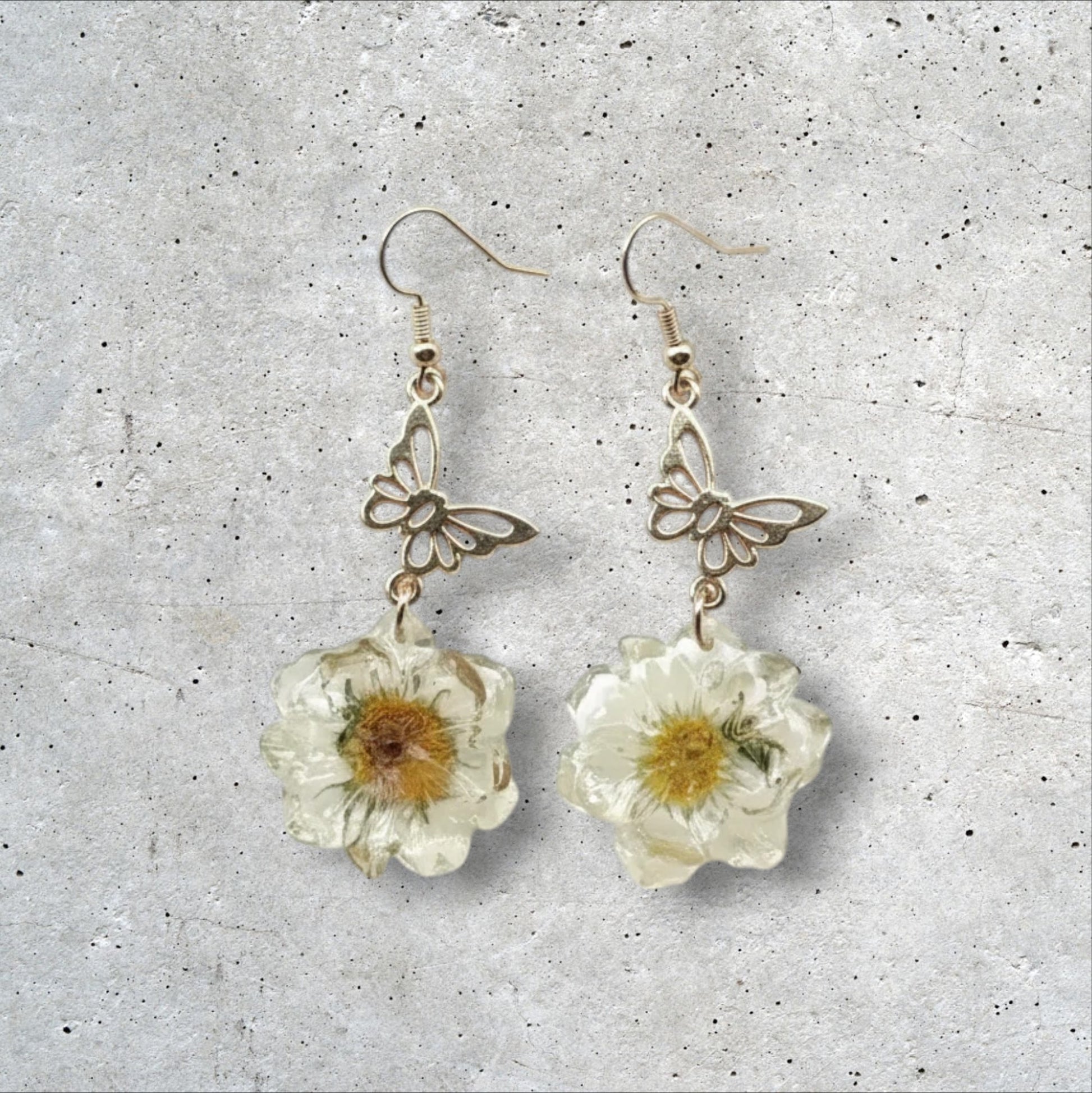 Alyssa's House gold-tone butterfly earrings featuring cream pressed flowers in a whimsical vintage style.