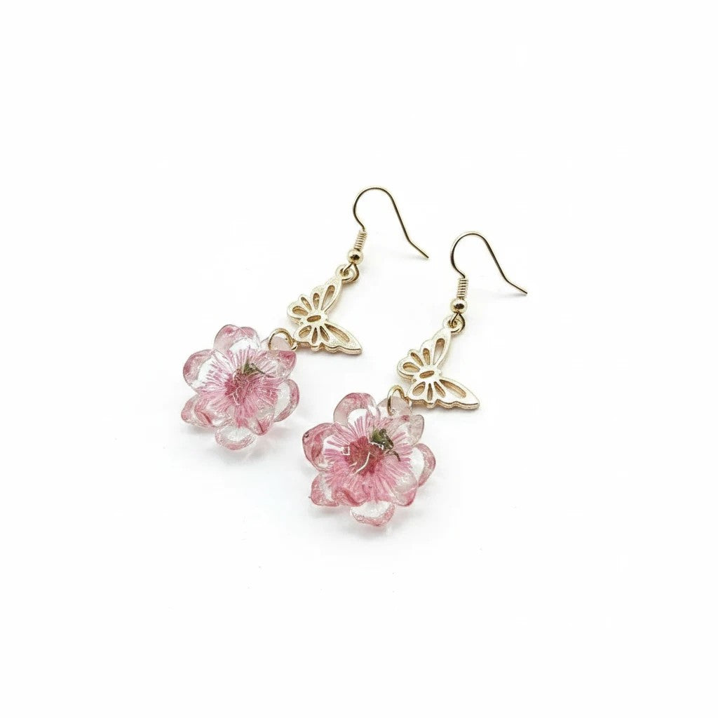 Alyssa's House gold-tone butterfly earrings featuring delicate pink pressed flowers in a resin drop design.