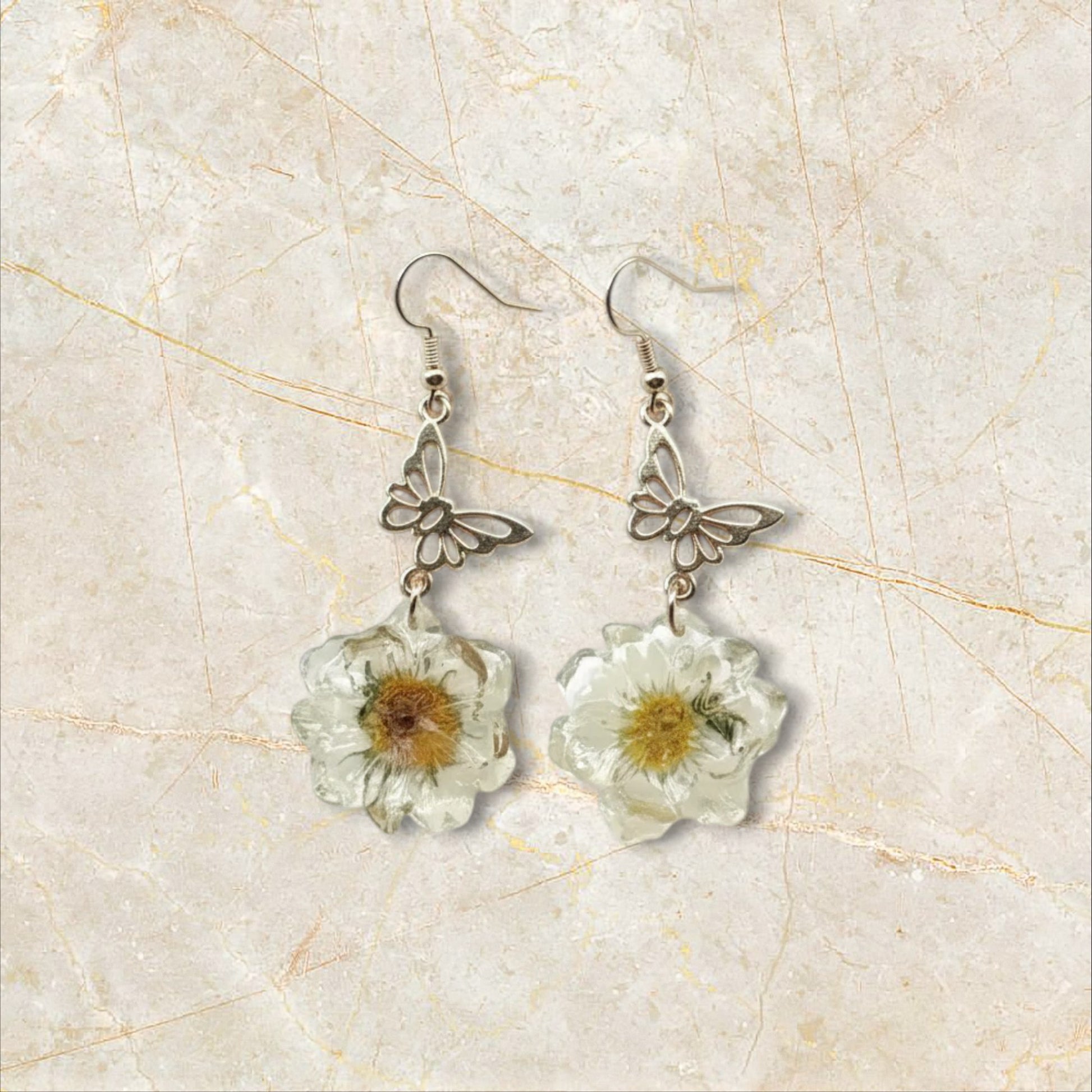Alyssa's House vintage-style earrings featuring gold-tone butterfly charms and cream pressed flower resin pendants.