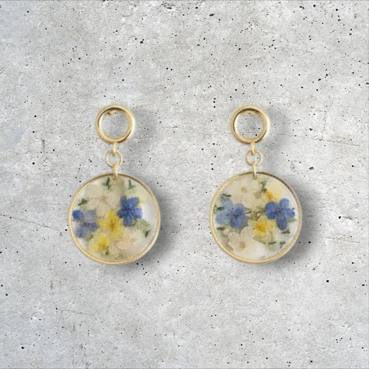 Alyssa's House round clear resin earrings featuring blue and yellow pressed flowers with gold-tone drop hooks.