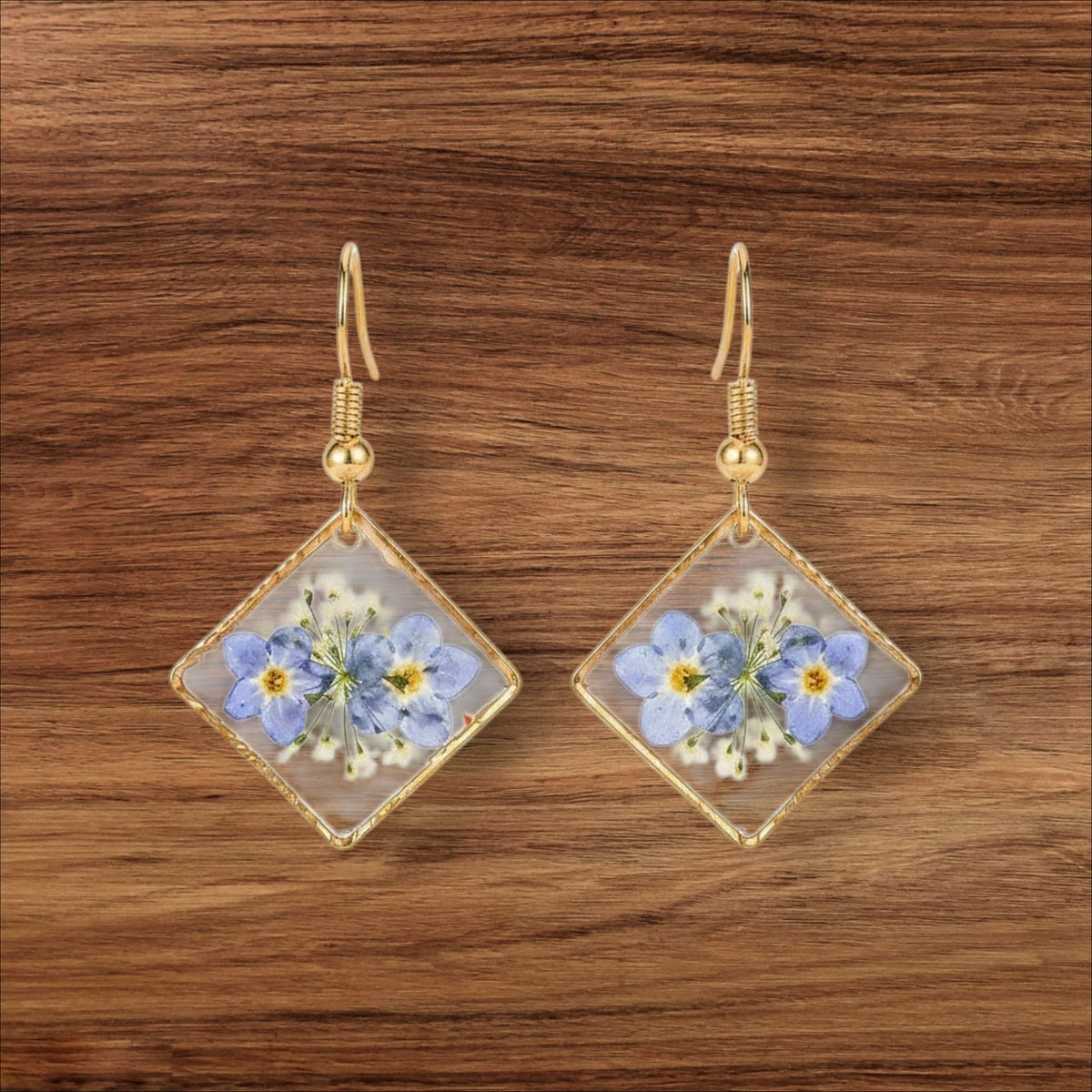Alyssa's House diamond-shaped resin earrings featuring pressed blue forget-me-not flowers in a gold-tone frame.