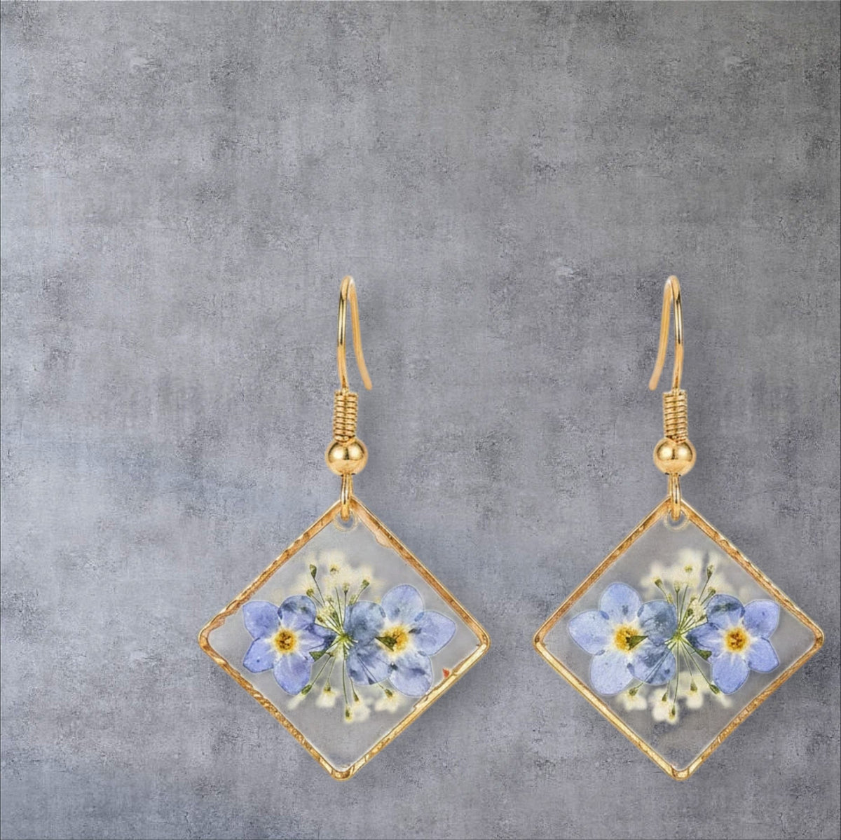 Alyssa's House diamond-shaped resin earrings featuring pressed blue forget-me-not flowers in a gold-tone frame.