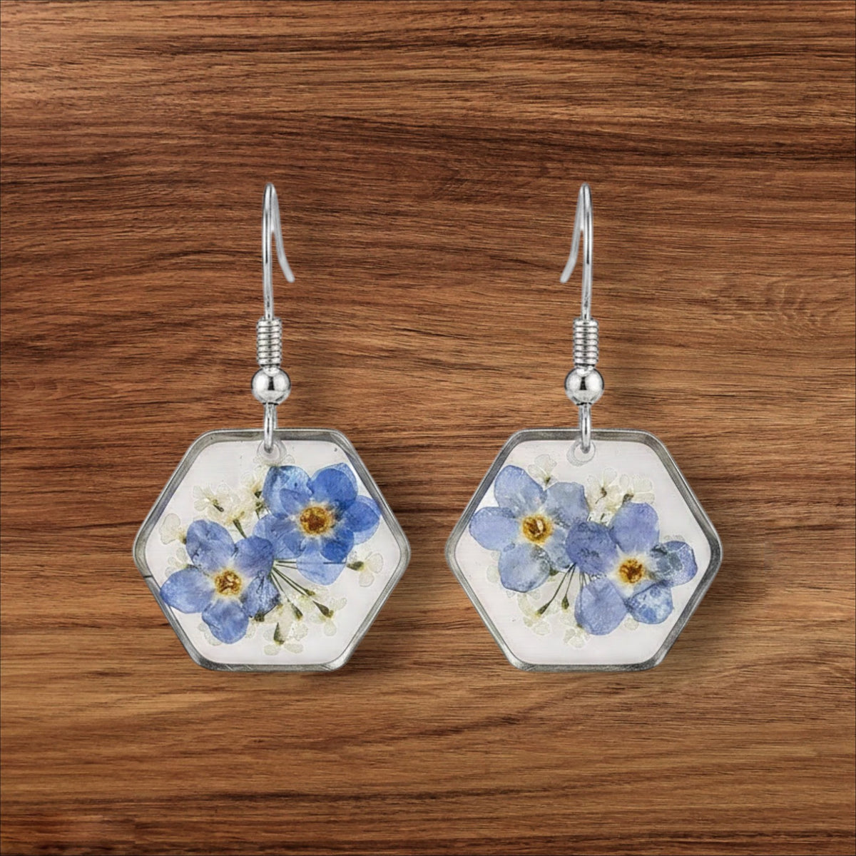Alyssa's House hexagon resin earrings featuring pressed blue forget-me-not flowers encased in silver-tone wire frames.