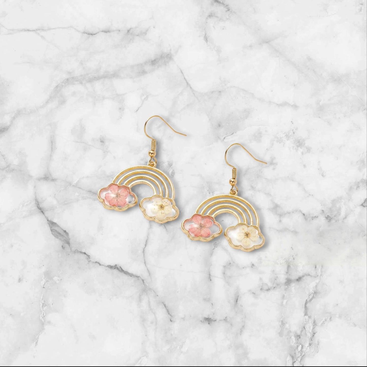 Alyssa's House gold-tone rainbow earrings featuring pressed pink and white flowers in cloud-shaped resin charms.