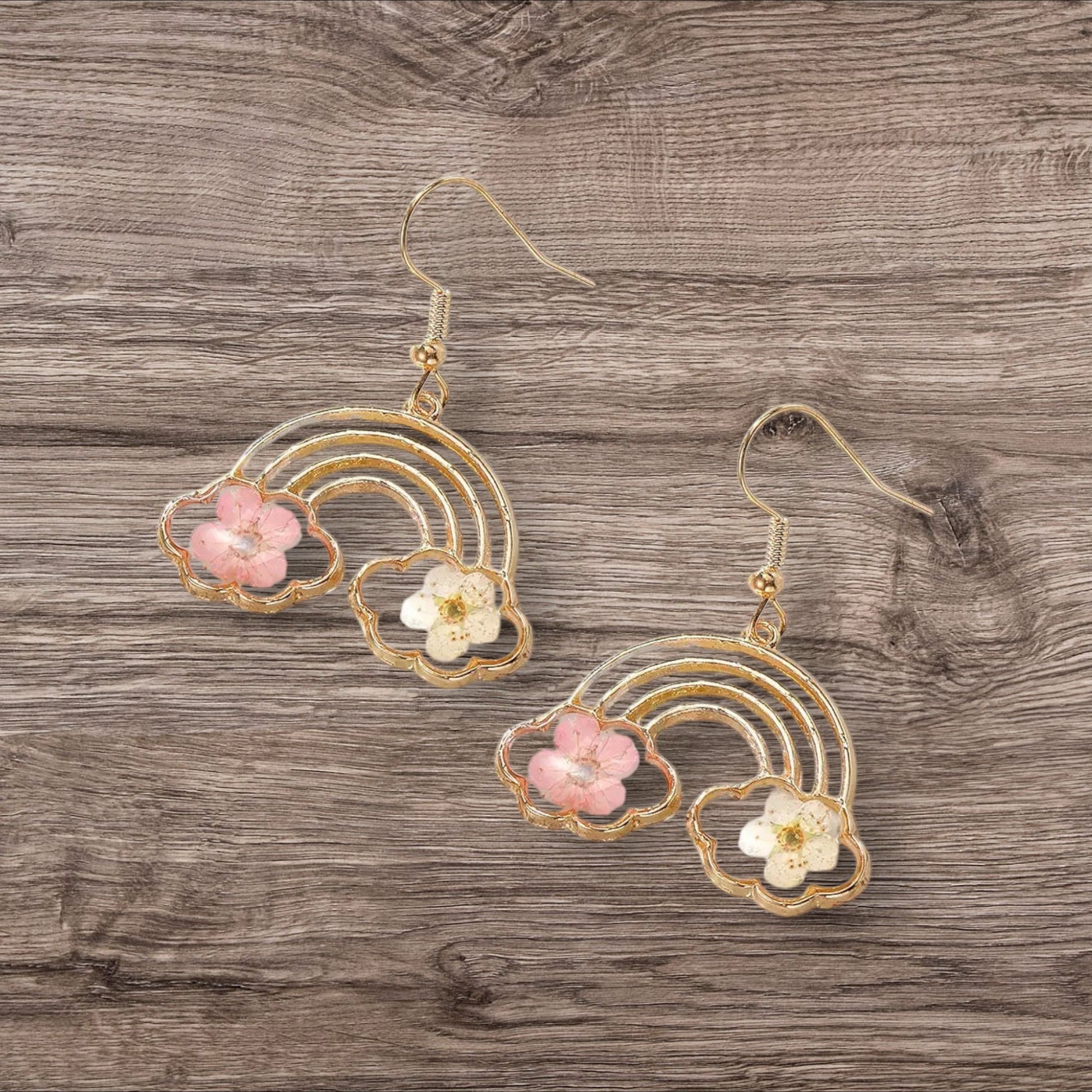 Alyssa's House gold-tone rainbow drop earrings featuring pressed pink and white flowers in a cheerful statement design.