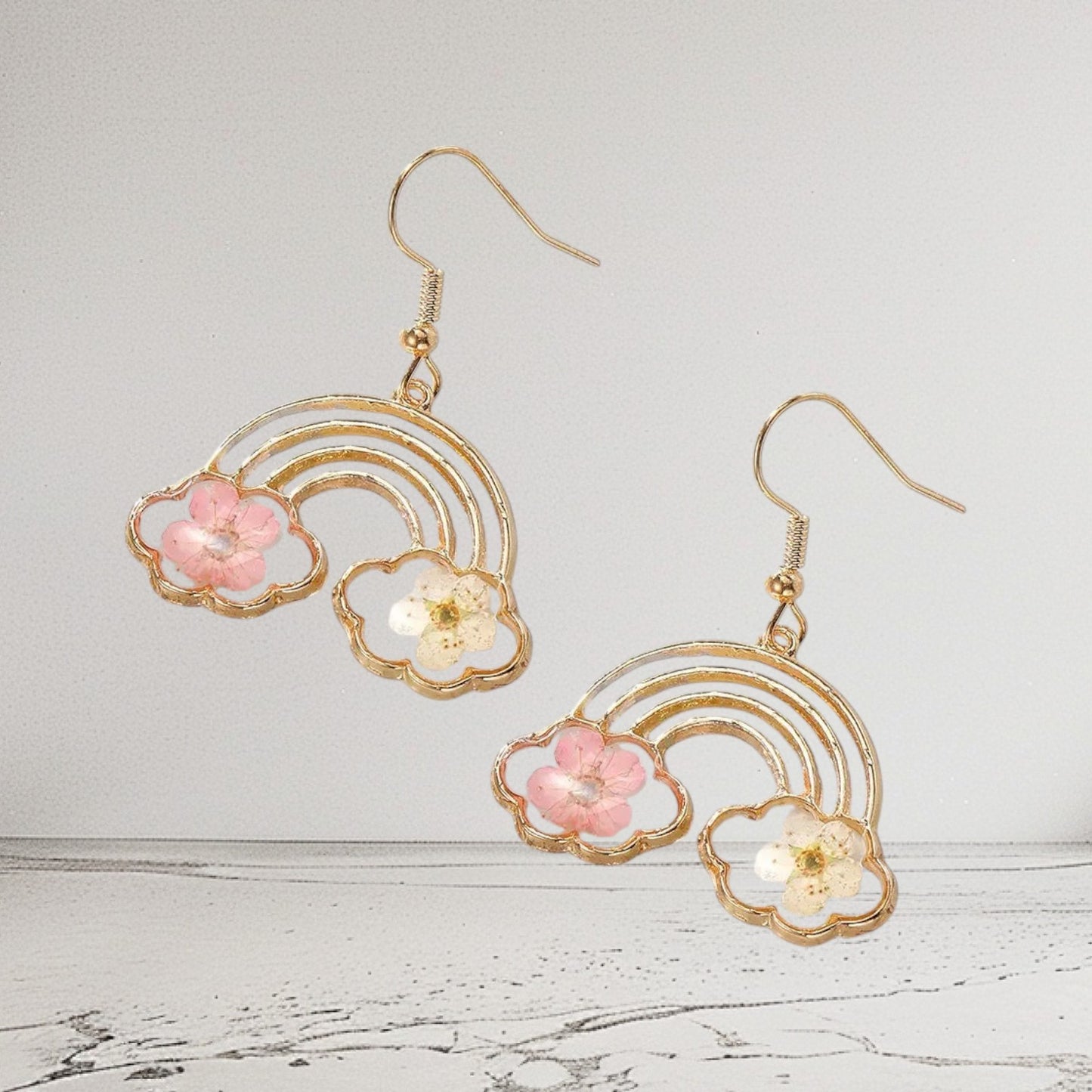 Alyssa's House gold-tone rainbow drop earrings featuring pressed pink and white flowers in a cheerful statement design.