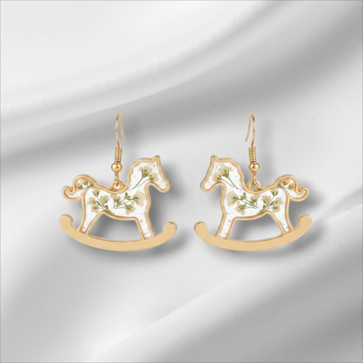 Alyssa's House gold-tone rocking horse earrings featuring clear resin bodies with delicate pressed flowers.