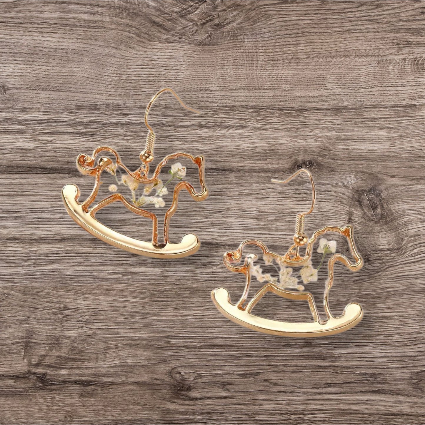 Alyssa's House gold-tone rocking horse earrings featuring clear resin bodies with delicate pressed white flowers.