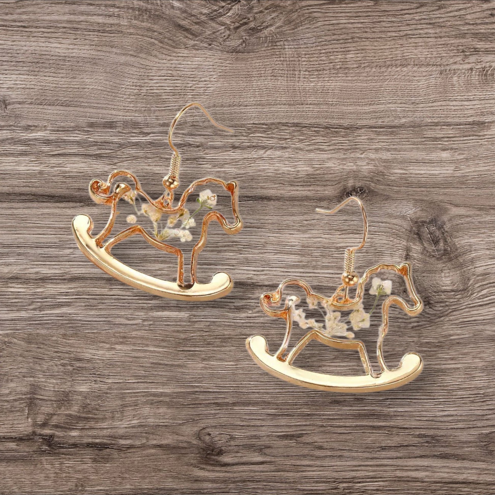 Alyssa's House gold-tone rocking horse earrings featuring clear resin bodies with delicate pressed white flowers.