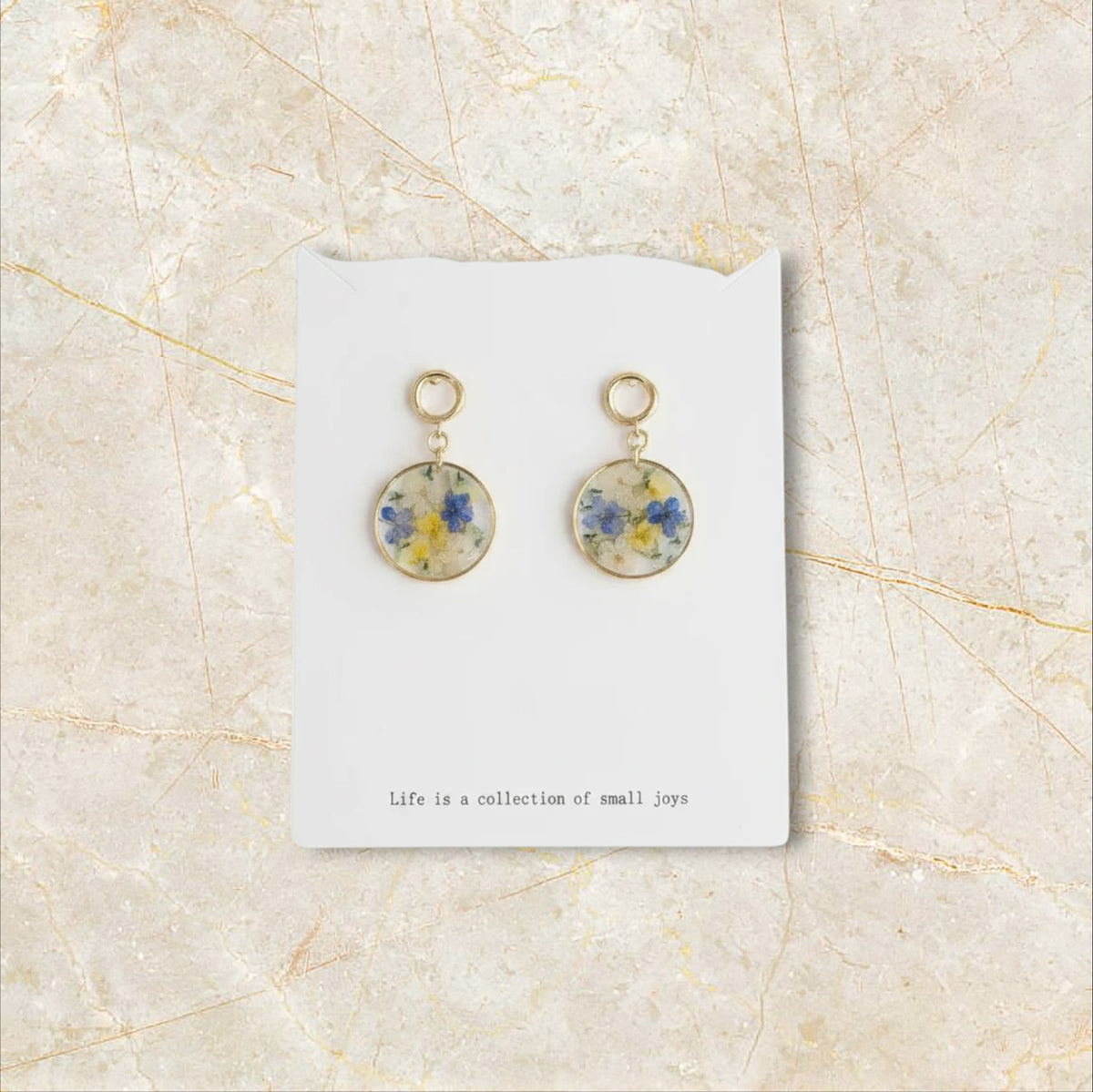 Alyssa's House round clear resin earrings featuring blue and yellow pressed flowers with gold-tone hooks.