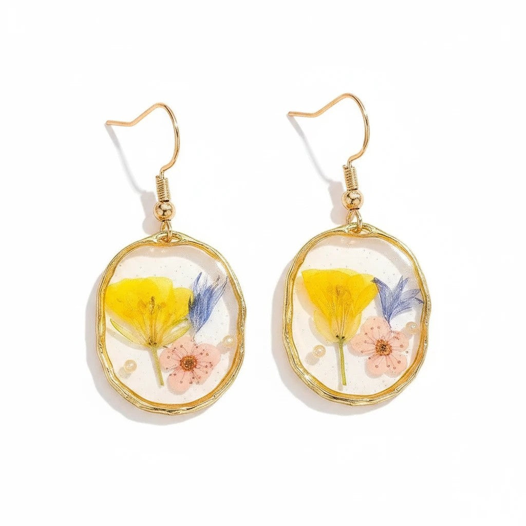 Alyssa's House oval resin drop earrings featuring pressed yellow and blue wildflowers inside a gold-tone rim.